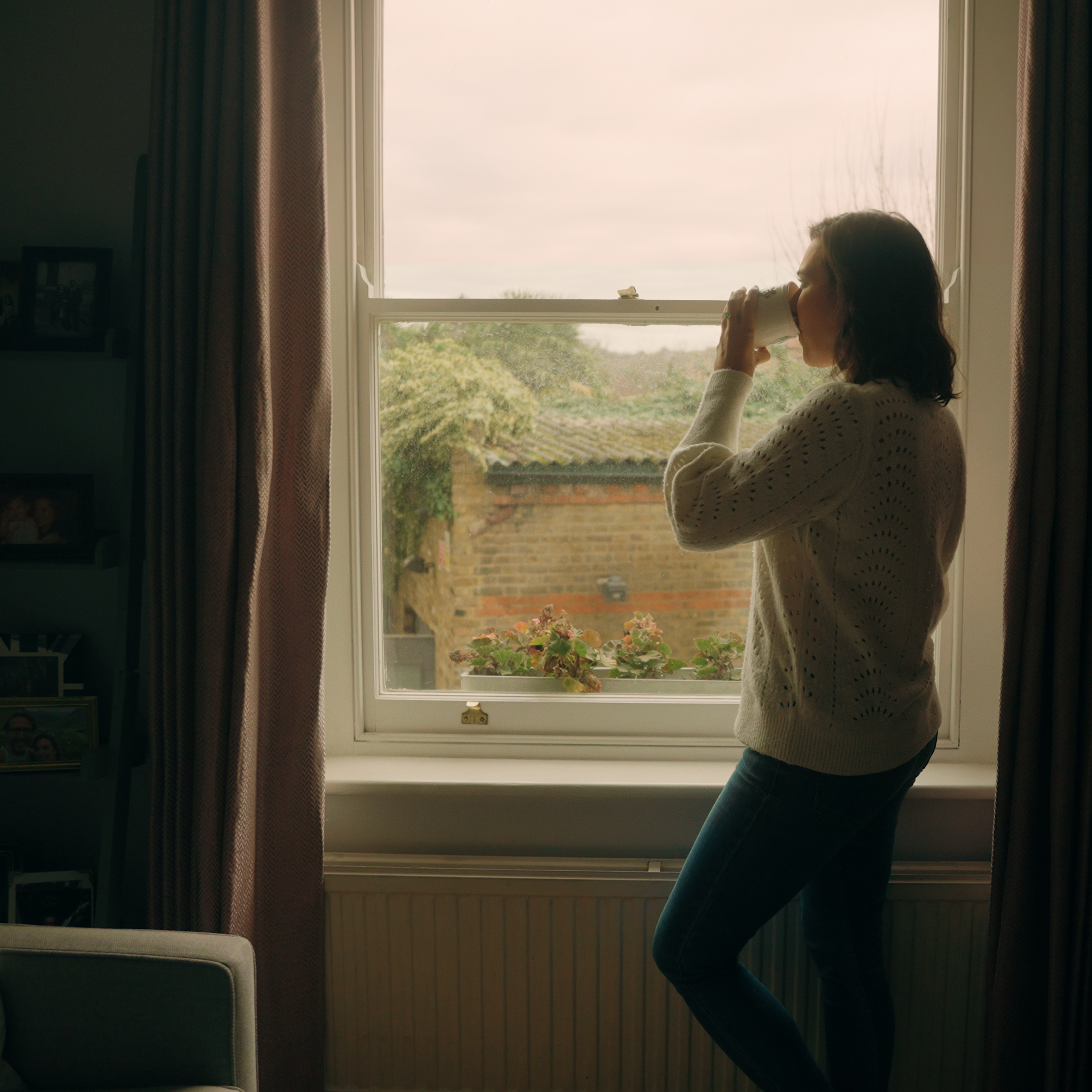 Woman drinking tea looking out window