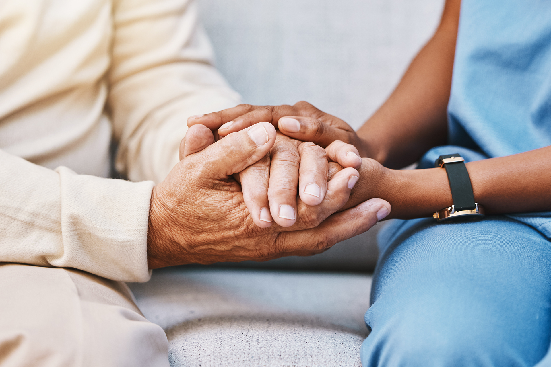 Two people sitting down holding hands