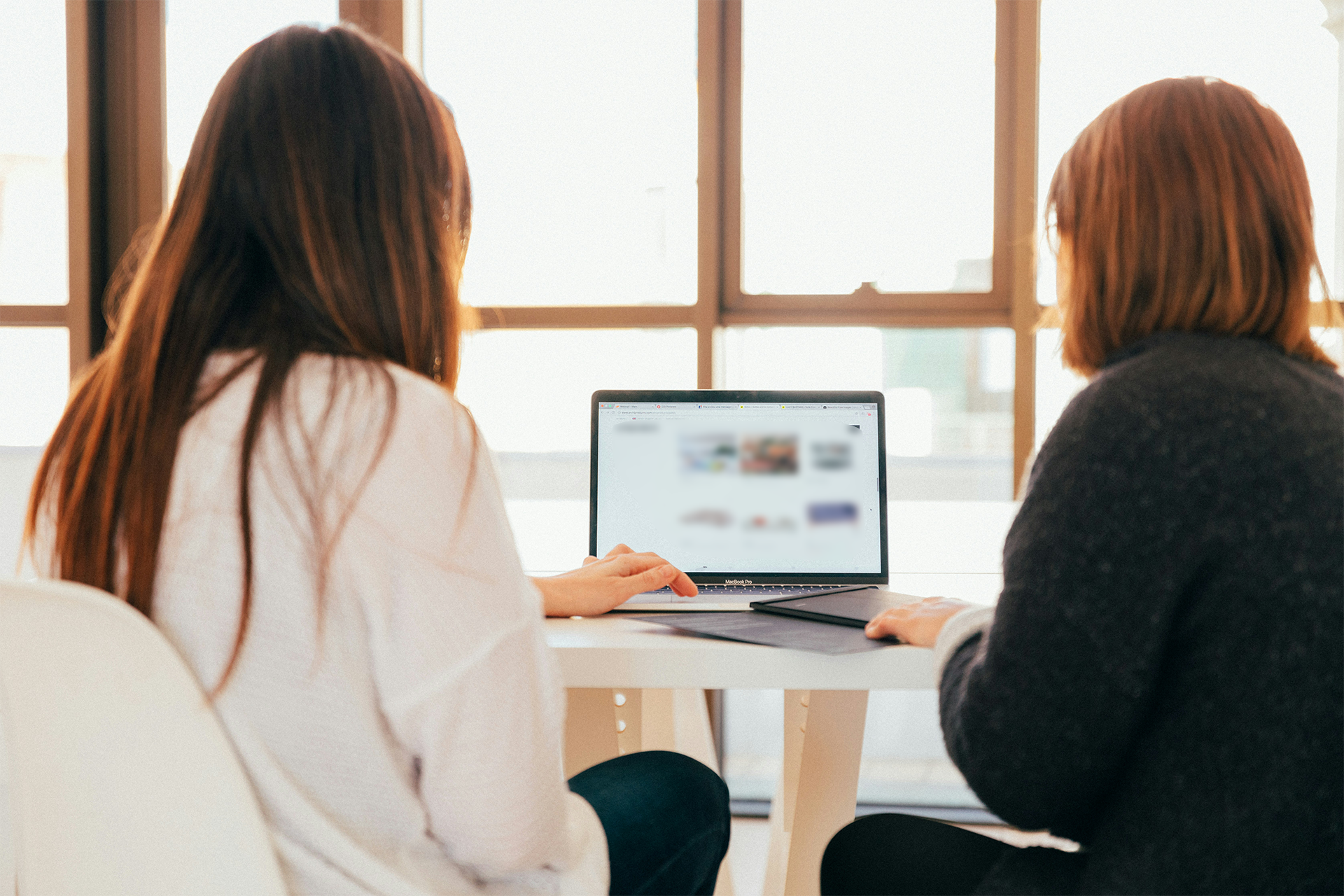 Two women looking at laptop and researching