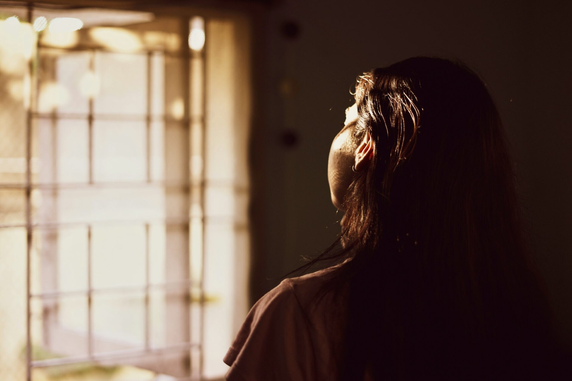 First Death Anniversary: Ways to Honour a Loved One 4 Person looking out of glowing window