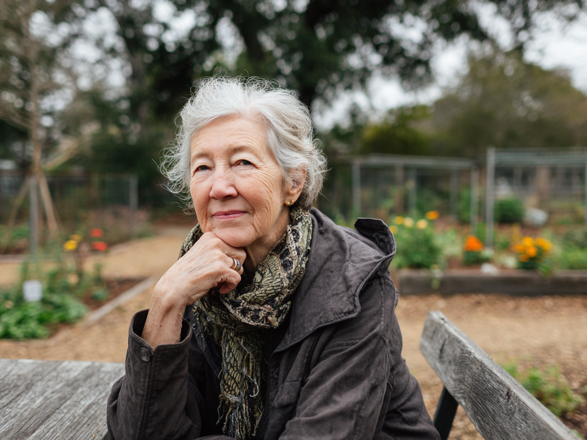 template-funeral-plans 23 Woman sitting in allottment looking into camera